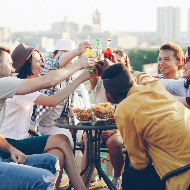 Friends toasting drinks on a rooftop at sunset